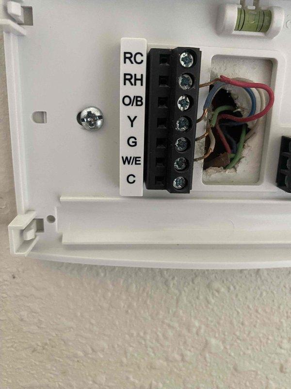 Replaced thermostat at customer's residence per management authorization. Disconnected existing thermostat wiring from terminal block, removed old unit from wall, and installed new thermostat with proper wire connections to RC, RH, O/B, Y, G, W/E, and C terminals. Verified system operation and temperature readings using calibrated digital thermometer, confirming proper HVAC functionality upon completion.