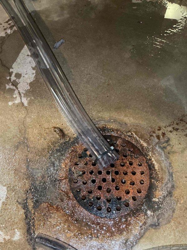 Responded to service call for water leaking from 16-year-old furnace system located in basement. Upon arrival, found significant water accumulation on concrete floor around HVAC unit with visible staining and moisture damage throughout mechanical room area. Identified condensate drainage issue with condensate lines routing to floor drain, which showed heavy rust and corrosion. Per customer instructions, shut down air conditioning system while leaving fan operational to prevent further water discharge. Documented extensive water damage on floor and compromised cardboard materials near equipment, indicating ongoing drainage problem requiring condensate system repair or replacement.