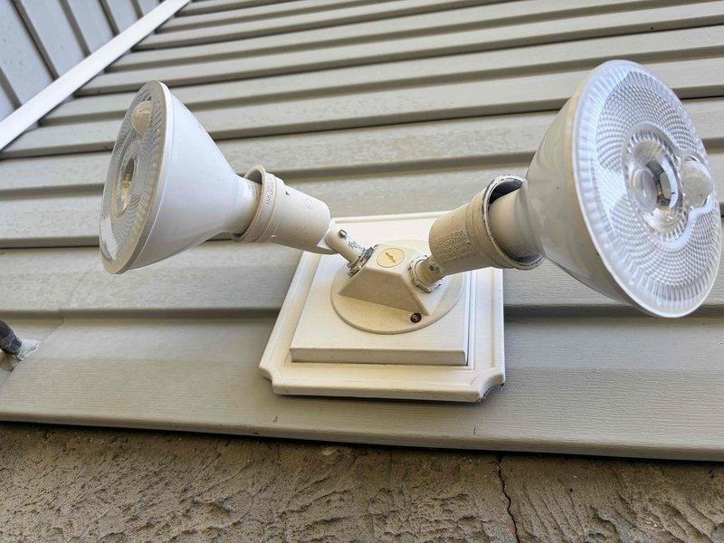 Completed electrical estimate for installation of new outdoor electrical outlet and ceiling fan. Assessed existing exterior electrical infrastructure including outdoor junction box mounted on deck railing and dual floodlight fixtures on vinyl siding. Evaluated routing requirements for 12-4 wire run from main panel to proposed exterior outlet location. Documented current outdoor lighting configuration and electrical access points to determine optimal installation pathway for new circuits. Verified adequate capacity for additional load and identified connection points for ceiling fan installation.