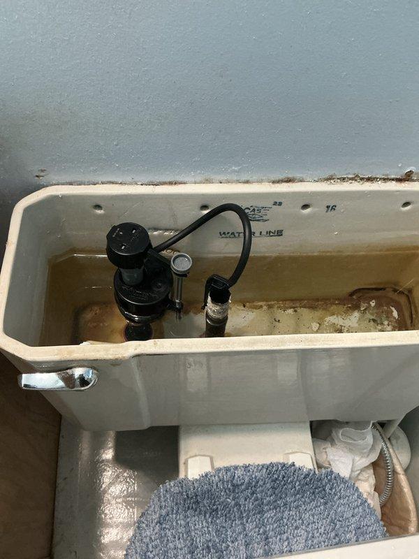 Responded to post-installation callback for low water pressure and popping noise at kitchen and bathroom sinks. Removed and cleaned faucet aerators which contained heavy mineral buildup and scale deposits causing restricted flow and noise. Inspected toilet tank which showed rust and mineral accumulation at base of flush valve assembly and interior surfaces; assessed condition and functionality of flush mechanism.