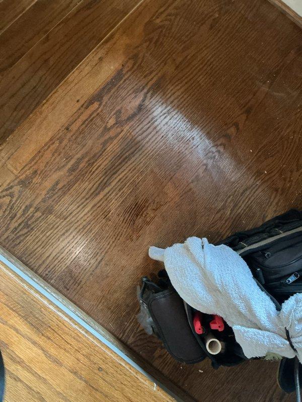 Responded to service call for attic-mounted A/C unit. Upon inspection, discovered significant ceiling damage around supply vent register, including cracked texture, peeling material, and exposed substrate indicating possible condensation or moisture intrusion from ductwork. Documented water staining on hardwood flooring below affected area, suggesting active or recent leak from HVAC system. Photographed damage for record and recommended further evaluation of ductwork insulation and drain line integrity to prevent continued moisture damage.