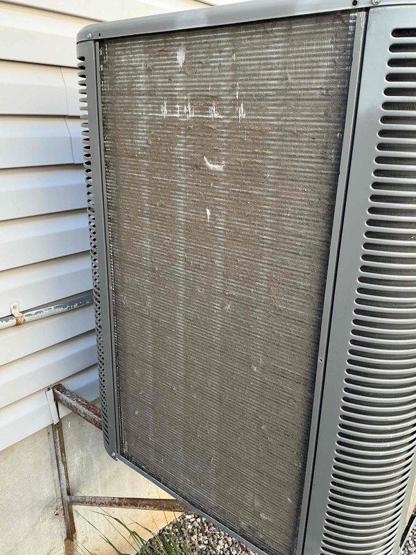 Completed comprehensive tune-up service on a 9-year-old residential air conditioning system located in a raised basement installation. Upon arrival, condenser coil exhibited heavy accumulation of dirt, dust, and environmental debris throughout the fin surfaces, significantly restricting airflow and reducing heat transfer efficiency. Performed thorough coil cleaning to restore proper airflow, inspected all electrical connections, verified refrigerant pressures, tested capacitor performance, and confirmed proper system operation. Unit returned to optimal operating condition with improved efficiency and airflow.