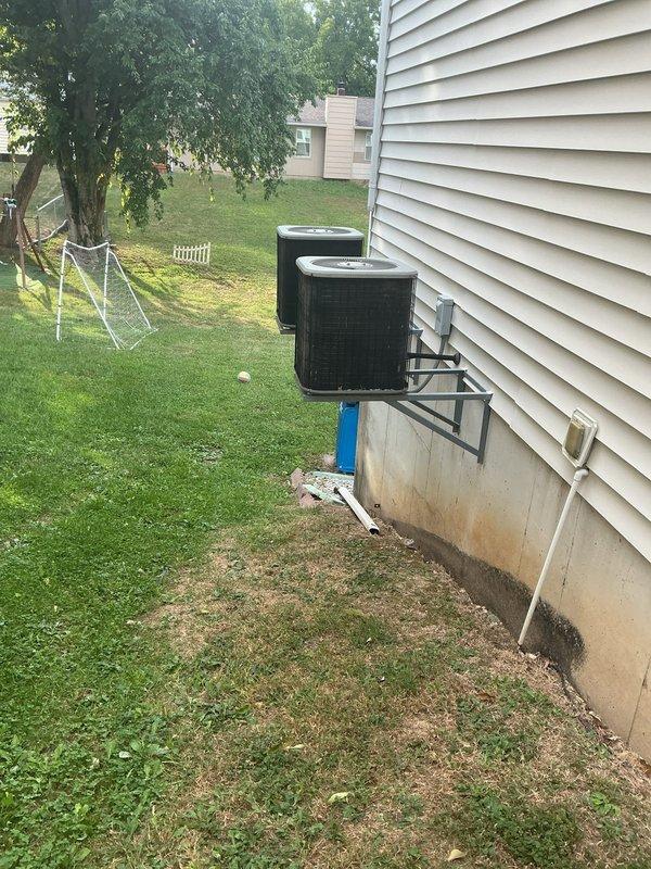 Responded to no cooling call for 20-year-old residential HVAC system. Upon arrival, performed diagnostic assessment of dual Lennox furnace installation in basement and exterior condenser units mounted on foundation. System was previously advised to be shut off due to cooling malfunction. Conducted visual inspection of indoor equipment, ductwork connections, and electrical components, then evaluated outdoor condenser units for operational issues. Documented equipment condition through photographic records showing both indoor furnace units with associated ductwork and piping, as well as exterior condenser placement and surrounding area conditions.