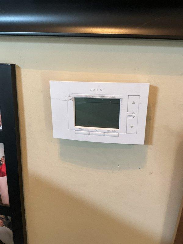Responded to no cooling complaint on 8-year-old Lennox air conditioning system affecting entire home. Performed diagnostic evaluation of outdoor condensing unit located in narrow side yard access area between structures. Inspected Sensi digital thermostat for proper operation and temperature differential. System evaluated for refrigerant levels, electrical components, airflow restrictions, and mechanical functionality to identify root cause of inadequate cooling performance.