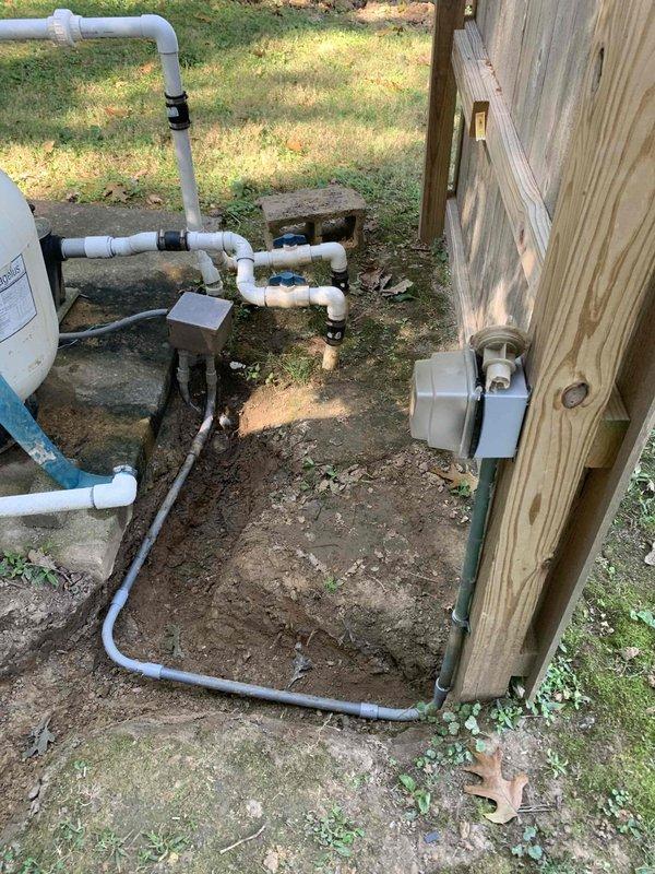 Relocated electrical service from existing shed-mounted installation to new fence post location. Installed weather-resistant meter box on wooden fence structure with proper mounting hardware and secured gray conduit running vertically along fence post to ground level. Routed electrical wiring through conduit system ensuring code-compliant installation and protection from environmental exposure. Verified all connections, tested system functionality, and confirmed proper grounding at new location.