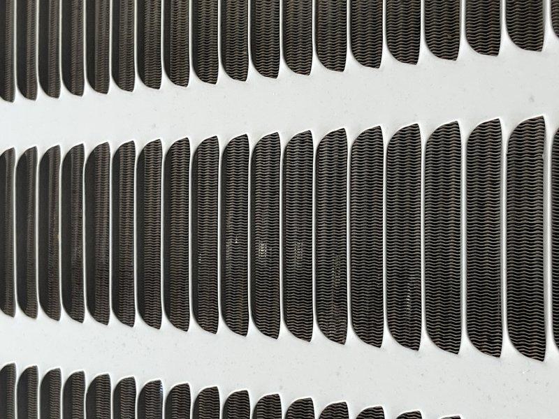 Responded to no cooling complaint with reported buzzing noise on 9-year-old system. Upon arrival, performed diagnostic evaluation of the outdoor condensing unit. Inspected condenser coil assembly and heat exchanger fins for proper airflow and operational integrity. Photographed coil condition showing parallel fin arrangement with uniform spacing and no visible damage or significant debris accumulation. Verified fin structure and spacing throughout multiple rows of the heat exchanger assembly. System evaluated for buzzing source and cooling capacity issues affecting entire HVAC operation.