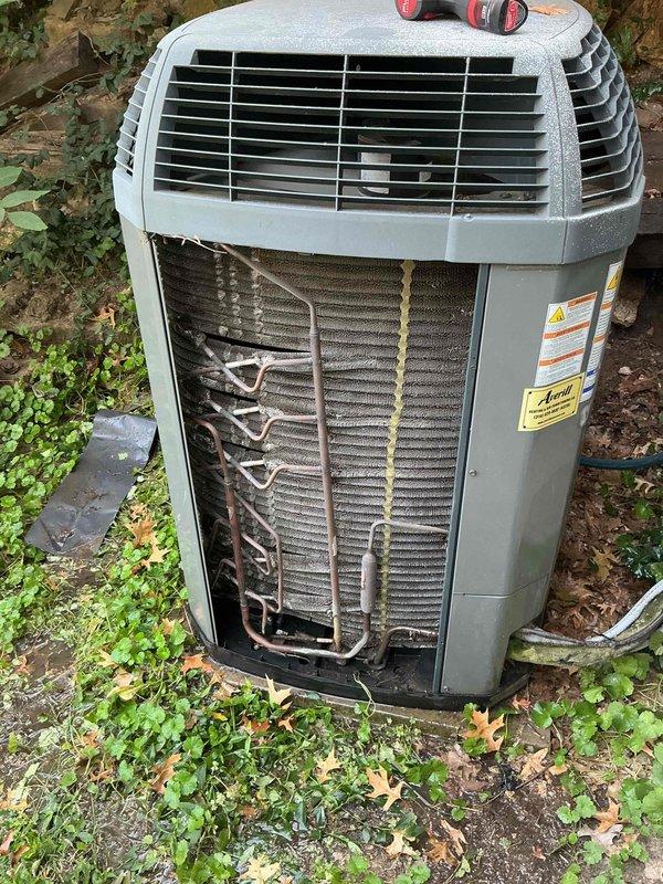 Responded to no-cooling complaint on 8-year-old Trane whole-house air conditioning system. Upon inspection, found outdoor condenser unit with significant dirt, dust, and debris accumulation on condenser coils and aluminum fins. Removed front access panel to assess internal components and refrigerant lines. Condenser coil showed heavy buildup restricting airflow through finned surfaces, which was likely contributing to reduced cooling capacity and system inefficiency. All copper refrigerant lines and connections appeared intact with no visible signs of leakage or damage. Unit structure and housing in acceptable condition for age. Documented internal component condition with photographs showing extent of coil contamination and overall system state for maintenance records.