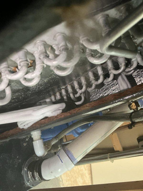 Responded to callback for AC system failing to cool adequately and running continuously without reaching set temperature. Upon inspection, found evaporator coil completely frozen with heavy ice buildup throughout entire coil assembly. Documented frozen coil condition with photographs showing thick frost accumulation on serpentine coils and surrounding components. Identified restricted airflow as primary cause of freezing condition. Checked air filter and found severely clogged, blocking proper airflow across evaporator coil. Replaced dirty air filter with new filter. Shut system down to allow coil to thaw completely before restart. Explained to customer that frozen coil prevents proper heat exchange and causes system to run continuously without cooling effectively. Advised that previous capacitor replacement was unrelated to current airflow restriction issue. Instructed customer on importance of regular filter maintenance every 30-60 days to prevent future freezing and system inefficie