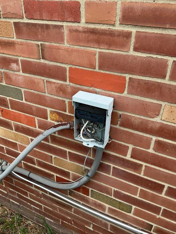 Responded to no cooling complaint on outdoor condensing unit over 10 years old located on side of home. Upon arrival, confirmed unit was not operating and customer had shut off power per prior instructions. Performed diagnostic inspection of aged condenser unit, which exhibited significant weathering, rust on grille and base components, and visible corrosion throughout. Inspected electrical junction box and conduit connections at exterior wall. Unit displayed abnormal noise symptoms as reported and failed to start properly. Documented equipment condition with photos showing deteriorated state of outdoor unit and electrical connections requiring attention.