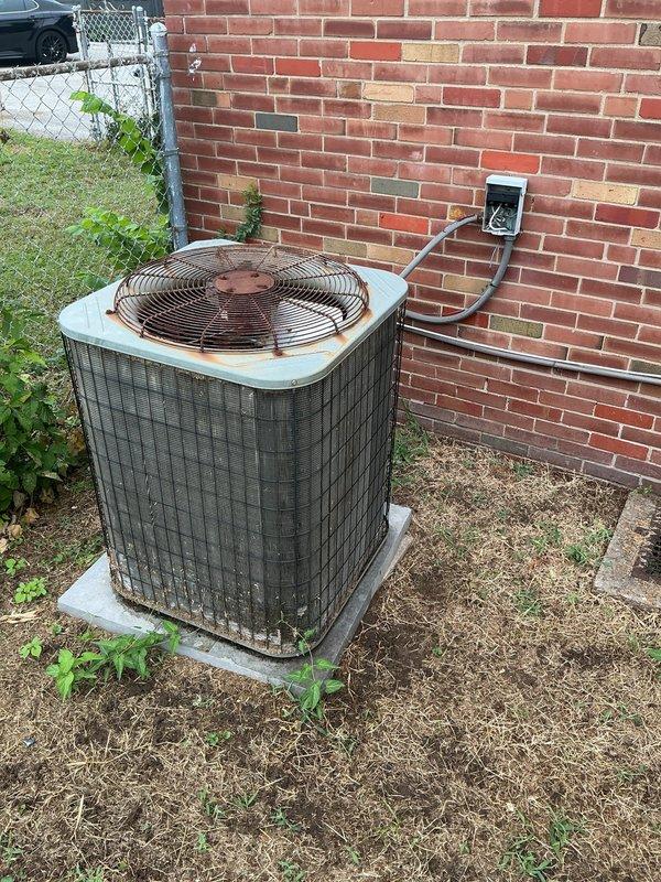 Responded to no cooling complaint on outdoor condensing unit over 10 years old located on side of home. Upon arrival, confirmed unit was not operating and customer had shut off power per prior instructions. Performed diagnostic inspection of aged condenser unit, which exhibited significant weathering, rust on grille and base components, and visible corrosion throughout. Inspected electrical junction box and conduit connections at exterior wall. Unit displayed abnormal noise symptoms as reported and failed to start properly. Documented equipment condition with photos showing deteriorated state of outdoor unit and electrical connections requiring attention.