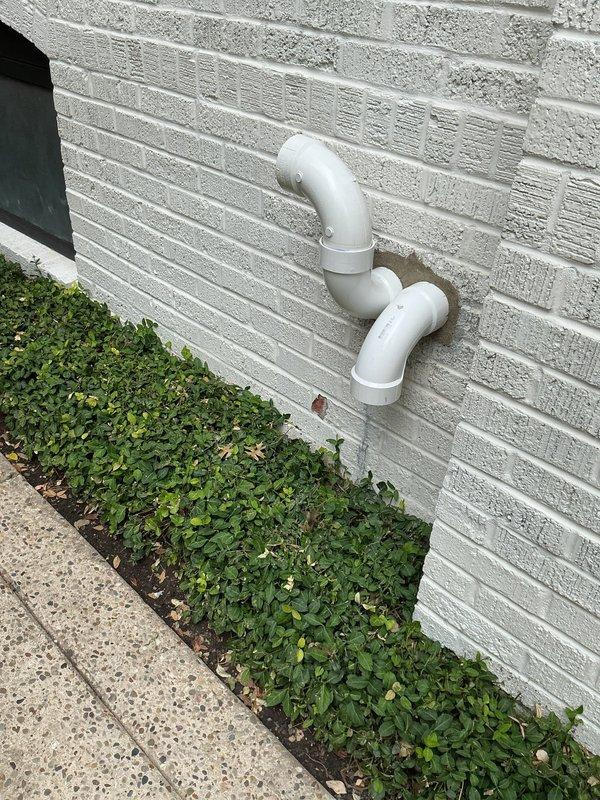 Returned to property to address PVC termination penetration through exterior wall. Removed deteriorated mortar around dual PVC pipe elbows and resealed penetrations with fresh mortar to ensure proper weatherproofing and structural integrity. Unit confirmed operational upon completion.