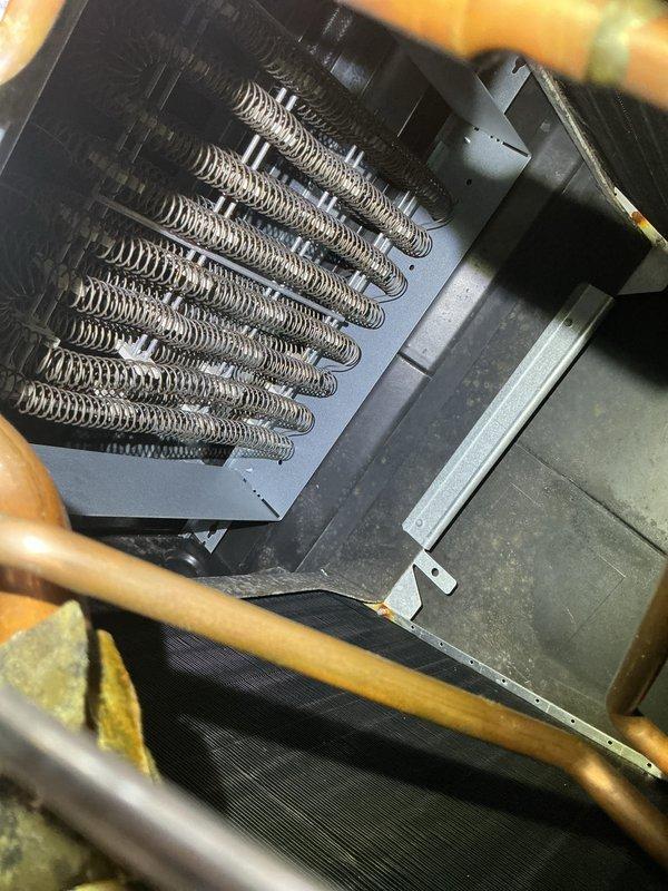 Performed comprehensive AC tune-up on 26-year-old York system per customer request based on thermostat reminder. Inspected evaporator coil assembly showing V-configuration with serpentine tubing arrangement, confirmed refrigerant lines and electrical connections secure with no visible leaks or damage. Accessed air handler unit in attic space, examined heating coil assembly and housing, noted minor dust accumulation typical for system age but overall components functioning properly with no immediate service concerns identified.