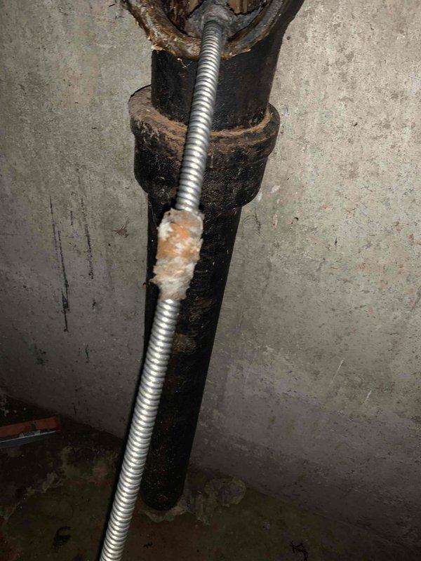 Responded to a clogged shower drain in the basement bathroom. Upon inspection, discovered deteriorated flexible metal conduit and damaged piping components in the drain line assembly. Cleared the obstruction and documented the compromised conduit sections that will require future replacement to prevent recurring drainage issues.