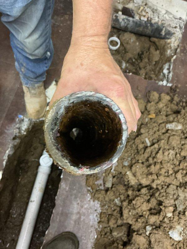 Replaced a 5-foot section of deteriorated sewer line in basement floor per permit 26PLU-18570. Excavated through concrete basement flooring to access the heavily corroded pipe, which exhibited significant internal buildup and reduced diameter from rust and mineral deposits. Removed the failed section and installed new white PVC piping with proper fittings, backfilled the trench, and prepared the area for inspection.