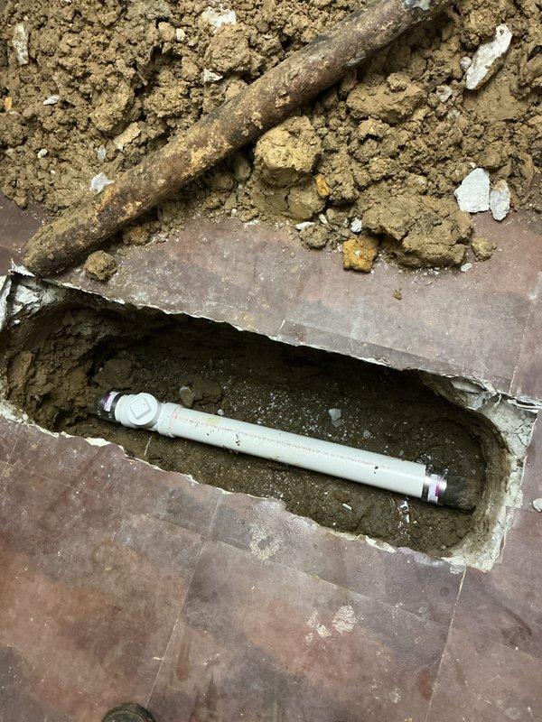 Replaced a 5-foot section of deteriorated sewer line in basement floor per permit 26PLU-18570. Excavated through concrete basement flooring to access the heavily corroded pipe, which exhibited significant internal buildup and reduced diameter from rust and mineral deposits. Removed the failed section and installed new white PVC piping with proper fittings, backfilled the trench, and prepared the area for inspection.