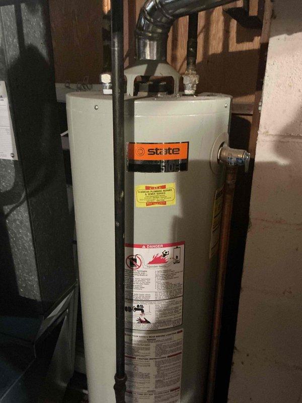 Replaced existing 6-year-old water heater with new 40-gallon gas short State brand tanked water heater in basement utility area. Installation included connecting copper supply lines, installing 3/4-inch ball valve, and routing black gas piping to unit. All plumbing connections were secured with proper fittings and tested for leaks. Verified proper venting configuration and clearances from surrounding equipment including adjacent water softener. Confirmed all safety labels and warning decals were visible and intact on new unit. System was pressurized, filled, and tested for proper operation with no leaks detected at any connection points.