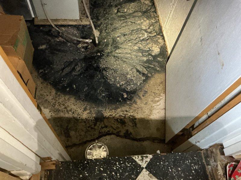 Responded to main floor drain backup in basement. Upon arrival, found extensive sewage water damage in basement corner with significant black water contamination spread across floor area. Accessed cleanout location in backyard through exterior sliding door entrance. Performed time and materials cleanout service on main sewer line to clear obstruction causing basement drain backup. Successfully restored proper drainage flow through ground water drain system. Backup was resolved and system returned to normal operation.