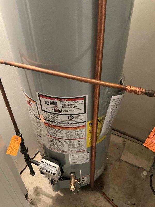 Responded to service call for no hot water and gas odor at residential property. Removed existing failed gas water heater from utility closet and installed new 40-gallon natural gas atmospheric vent water heater. Connected copper supply lines, gas piping with shutoff valve, temperature and pressure relief valve discharge piping, and verified proper venting. Tested all connections for leaks, confirmed proper gas combustion, and verified unit operation meets manufacturer specifications and local code requirements.