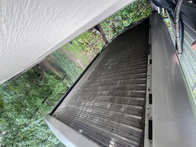 Responded to no cooling complaint with "GFHS I sense open" fault displayed on Lennox programmable digital thermostat. Upon arrival, accessed property using provided entry code and inspected system components. Examined outdoor condensing unit located beneath deck structure and found evaporator coils heavily soiled with dirt, dust, and debris accumulation causing restricted airflow. Opened access panel to assess coil condition and confirmed significant buildup across fin surfaces with visible streaking and discoloration. Verified thermostat fault related to system sensor issue on approximately 10-year-old unit originally installed by Classic Aire Care. Documented equipment condition with photographs showing extent of coil contamination and moisture present on unit housing, indicating recent system operation attempts prior to service call.