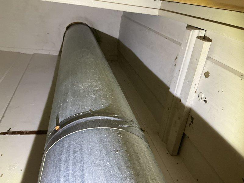 Responded to water leak complaint on 2-year-old Lennox system with uninsulated ductwork installed 3-4 years ago. Inspected attic ductwork and identified condensation issues on metal supply ducts running from attic to both floors of residence. Previous repair had been completed on one section of ductwork; however, discovered additional uninsulated duct section experiencing similar condensation problems resulting in water damage and mold growth in affected areas. Documented conditions with photographs showing uninsulated cylindrical metal duct in attic space and interior ceiling damage in kitchen area. Assessed extent of water damage and mold contamination requiring remediation. Recommended complete insulation of all exposed ductwork in unconditioned attic space to prevent future condensation during cooling season and additional water intrusion damage to structure.