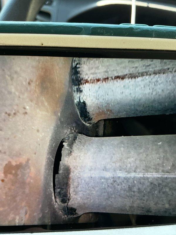Responded to service call for active water leak on 17-year-old air conditioning system. Upon arrival, performed diagnostic inspection of indoor and outdoor units to identify source of heavy leaking. Inspection revealed severely corroded evaporator coil and associated refrigerant lines with extensive rust, pitting, and oxidation damage throughout metal surfaces. Corrosion present on both horizontal refrigerant lines and vertical ductwork connections, with visible water damage and deterioration at seams and connection points. Advanced age of system combined with moisture exposure has compromised protective coatings and metal integrity. Documented condition with photographs showing extent of corrosion on coil assembly and ductwork components. Due to age of equipment and severity of deterioration, recommended system replacement as most cost-effective solution versus repair of compromised components.