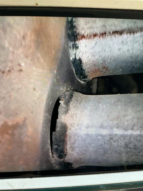 Responded to service call for active water leak on 17-year-old air conditioning system. Upon arrival, performed diagnostic inspection of indoor and outdoor units to identify source of heavy leaking. Inspection revealed severely corroded evaporator coil and associated refrigerant lines with extensive rust, pitting, and oxidation damage throughout metal surfaces. Corrosion present on both horizontal refrigerant lines and vertical ductwork connections, with visible water damage and deterioration at seams and connection points. Advanced age of system combined with moisture exposure has compromised protective coatings and metal integrity. Documented condition with photographs showing extent of corrosion on coil assembly and ductwork components. Due to age of equipment and severity of deterioration, recommended system replacement as most cost-effective solution versus repair of compromised components.