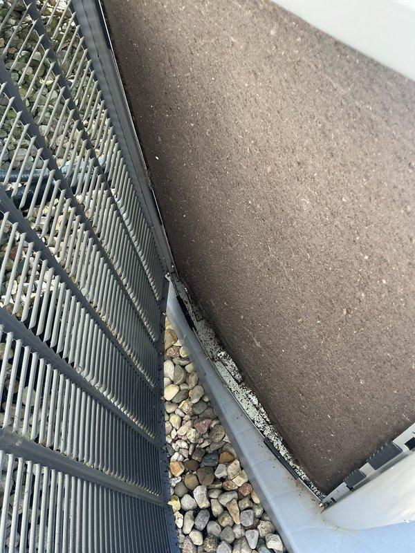Responded to service call for outdoor condensing unit experiencing loud banging noise, vibration, and intermittent shutdown under first-year warranty coverage. Upon inspection, discovered significant debris accumulation in condenser coil fins and surrounding components, which can cause airflow restriction, increased operating pressures, and potential compressor cycling issues. Documented unit condition with photographs showing heavy dirt buildup on exterior panels and within finned coil assembly, along with gravel and debris lodged between components that could contribute to operational noise and vibration concerns reported by customer.