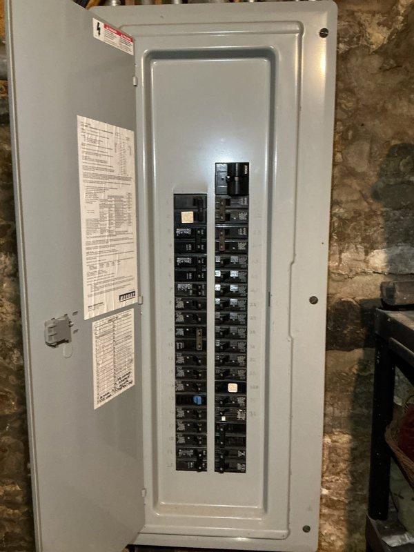 Responded to service call for non-functioning stairwell light fixture with suspected wire damage from recent AC installation. Upon arrival, accessed electrical panel to inspect circuit breakers and verify power distribution to affected fixture circuit. Photographed panel configuration showing dual columns of circuit breakers with directory labels for documentation purposes. Traced circuit serving stairwell lighting and confirmed panel integrity with all breakers properly seated and functional. Investigation revealed wiring issue consistent with customer's concern regarding recent HVAC work potentially compromising electrical connections. Restored power to stairwell fixture and verified proper operation upon completion.