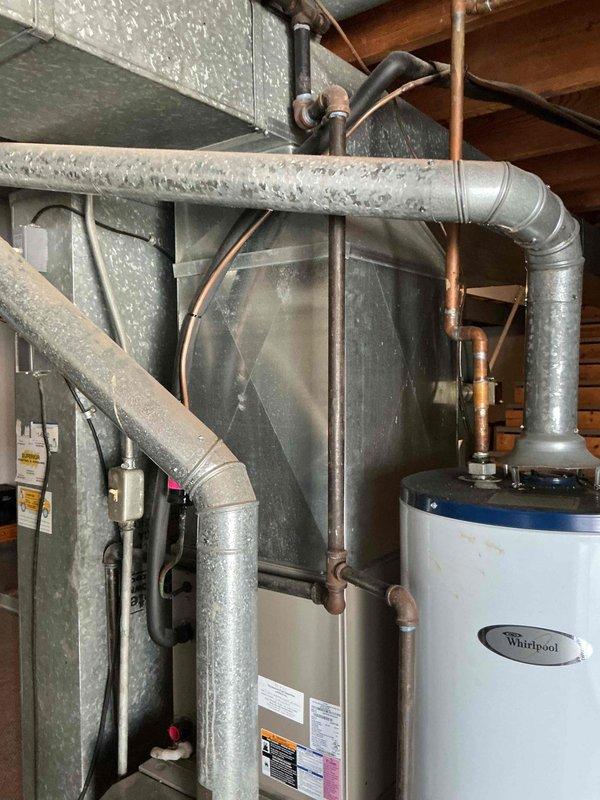 Replaced existing water heater with a new 50-gallon Whirlpool gas-fired tall model in basement mechanical room. Installed unit alongside existing HVAC equipment, connected copper supply lines and pressure relief valve, and verified proper operation of blue control valve assembly. Unit was staged for delivery with all plumbing connections completed and system tested for leaks and functionality.