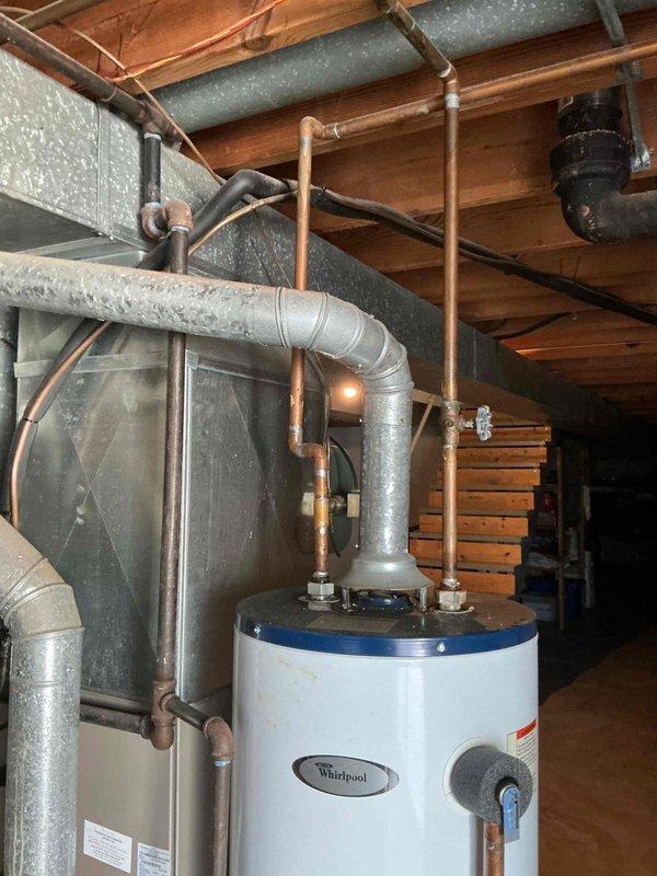Replaced existing water heater with a new 50-gallon Whirlpool gas-fired tall model in basement mechanical room. Installed unit alongside existing HVAC equipment, connected copper supply lines and pressure relief valve, and verified proper operation of blue control valve assembly. Unit was staged for delivery with all plumbing connections completed and system tested for leaks and functionality.