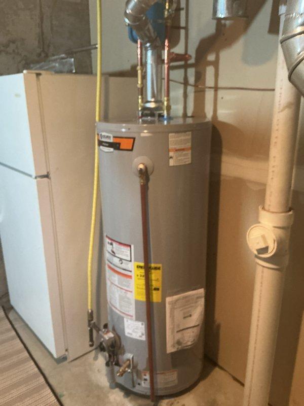 Successfully installed a 50-gallon gas tall water heater in residential basement utility area. Removed existing unit and positioned new water heater on wooden floor adjacent to existing HVAC equipment. Connected copper supply lines to top of unit with appropriate shut-off valves and installed yellow gas line connection on left side of tank. Verified all plumbing connections for proper seal and tested water flow through inlet and outlet ports. Installed temperature and pressure relief valve with discharge pipe per manufacturer specifications. Connected to existing metallic venting system routing through ceiling joists for proper exhaust ventilation. Tested gas line connections for leaks using approved detection methods and confirmed proper gas flow to burner assembly. Filled tank and purged air from system, then lit pilot light and verified burner ignition and flame characteristics. Confirmed all manufacturer labels and safety warnings remain visible and legible on tank exterior. Inspec