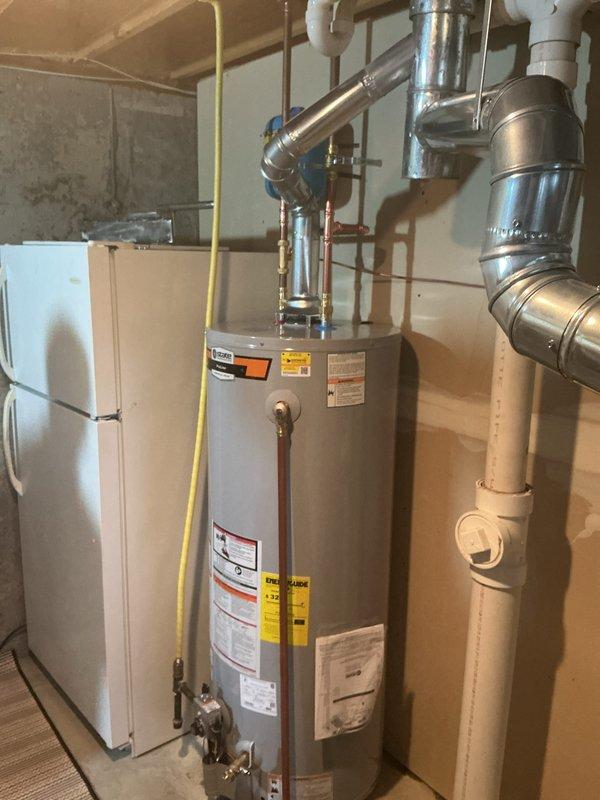 Successfully installed a 50-gallon gas tall water heater in residential basement utility area. Removed existing unit and positioned new water heater on wooden floor adjacent to existing HVAC equipment. Connected copper supply lines to top of unit with appropriate shut-off valves and installed yellow gas line connection on left side of tank. Verified all plumbing connections for proper seal and tested water flow through inlet and outlet ports. Installed temperature and pressure relief valve with discharge pipe per manufacturer specifications. Connected to existing metallic venting system routing through ceiling joists for proper exhaust ventilation. Tested gas line connections for leaks using approved detection methods and confirmed proper gas flow to burner assembly. Filled tank and purged air from system, then lit pilot light and verified burner ignition and flame characteristics. Confirmed all manufacturer labels and safety warnings remain visible and legible on tank exterior. Inspec