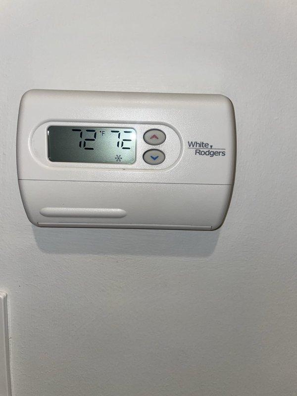 Responded to service call for malfunctioning thermostat controlling two 9-year-old HVAC units located in basement. Upon arrival, inspected White-Rodgers digital thermostat displaying 72°F in cooling mode. Removed cover to perform diagnostic evaluation of internal components, checking battery condition, circuit board integrity, and terminal wiring connections. Verified proper installation of Duracell AA batteries with secure spring contacts. Examined green circuit board (model 4588) for any signs of component failure or damage. Inspected all wire terminations at terminal block, confirming red, white, and blue wires were properly seated in connector tabs. Tested thermostat functionality and temperature control buttons to ensure proper communication with HVAC system. Documented equipment condition with photographs showing both exterior and interior components for service records.