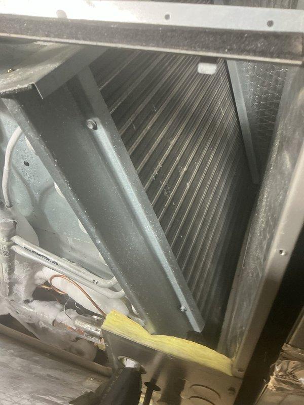 Responded to no-cooling complaint on downstairs 10-year-old A/C unit unable to reach setpoint temperature. Performed system inspection and accessed air handler to evaluate evaporator coil and airflow components. Inspected evaporator coil fins for cleanliness and proper condition, confirmed coil integrity and adequate fin spacing. Verified filter installation and positioning within plenum tracks, documented filter media condition and airflow pathway. Photographed internal components including heat exchanger assembly, blower housing, and filter plenum for service records.