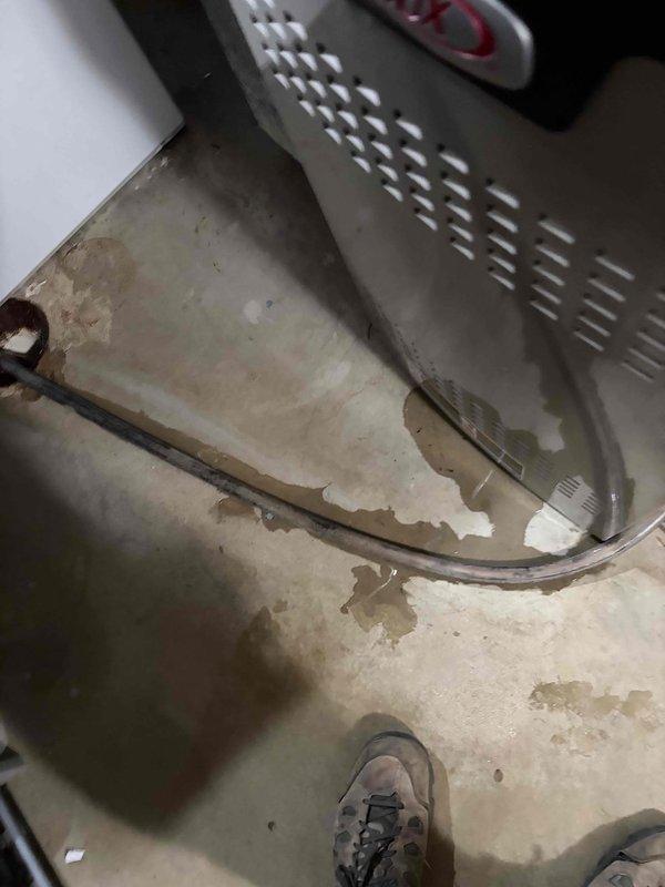 Responded to callback for 3-year-old Lennox system displaying alert code 207 and water leakage from AC unit despite maintaining cooling function. Upon inspection, discovered significant water accumulation and staining on floor beneath air handler, active condensation present in drain pan, and severe corrosion along drain pan seams with deteriorated coating. Identified compromised drain pan integrity as source of water leakage causing system alert. Documented conditions with photographic evidence showing rust damage and moisture intrusion requiring drain pan replacement to prevent further water damage and resolve alert code.