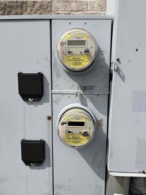 Responded to service call for commercial electrical outlet assessment. Upon arrival, performed comprehensive evaluation of exterior electrical outlets requiring replacement. Inspected dual-outlet configuration including standard duplex receptacle and GFCI outlet mounted on exterior wall with weathered trim board. Conducted electrical testing using portable GFCI circuit tester to verify ground fault protection functionality and circuit integrity. Evaluated electrical meter panel installation containing dual digital utility meters with associated conduit and protective enclosures. Documented existing conditions through photographic evidence showing outlet configuration, protective devices, and meter infrastructure. Provided estimate for outlet replacement work addressing weathering concerns and ensuring code-compliant GFCI protection for exterior receptacles.