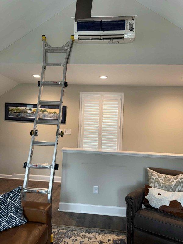 Responded to service call for mini-split unit experiencing water leakage and visible black contamination. Accessed wall-mounted air handler unit in vaulted ceiling area using extension ladder to inspect and address drainage issue. Cleared condensate line obstruction, cleaned contaminated surfaces from unit, and verified proper drainage function to resolve water dripping concern.