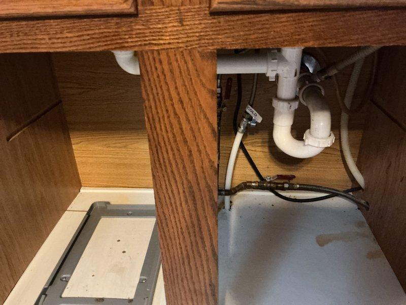 Responded to service call for clogged dual basin kitchen sink at single-family residence. Upon arrival, performed diagnostic assessment of black composite double-bowl sink with standing water and drainage issues in both basins. Inspected under-sink plumbing configuration, including white PVC P-trap assembly, drain connections, and water supply lines with braided flexible hoses and angle stop valves. Identified blockage in drain system preventing proper water flow. Utilized appropriate drain clearing tools and techniques to remove obstruction from drainage pipes. Tested both basins for proper water flow and drainage function following clearance procedure. Verified P-trap connections remained secure and leak-free. Confirmed successful restoration of full drainage capability in both sink basins. Documented conditions with photographs for service records.