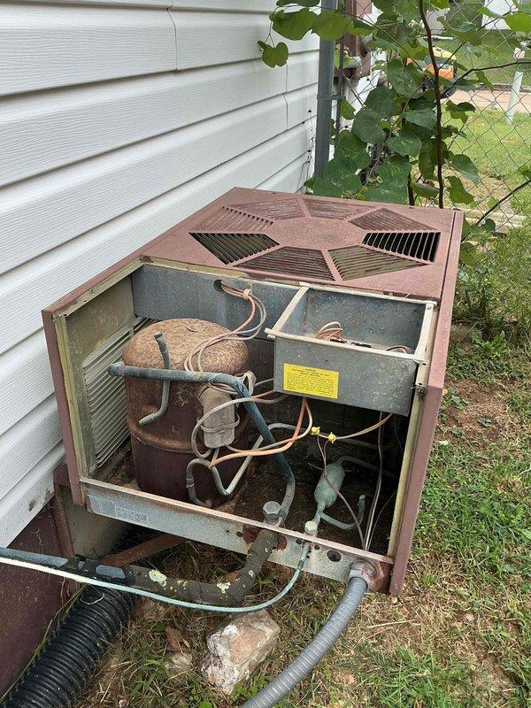 Responded to no cooling complaint on residential air conditioning system. Upon arrival, found aging outdoor condensing unit with cabinet panels removed for inspection. Visual assessment revealed extensive weathering, corrosion, and dirt accumulation on internal components including compressor housing, refrigerant lines, and electrical connections. Unit exhibited significant oxidation on metal surfaces and deteriorated cabinet finish consistent with extended outdoor exposure. Documented equipment condition with photographs showing internal mechanical components, copper refrigerant tubing, and overall system degradation. Based on age and visible wear of equipment, provided assessment findings to customer regarding cooling system performance issues.