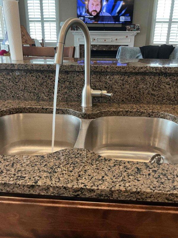 Responded to service call for kitchen sink producing gurgling sounds during drainage. Upon inspection, confirmed sink was draining properly with no standing water or slow drainage issues. Examined the double-bowl undermount sink configuration with garbage disposal installed on one basin. Inspected under-sink plumbing including disposal unit, P-trap assembly, and PVC drain connections. Gurgling noise typically indicates a venting issue or partial blockage in the drainage system allowing air to be pulled through the trap. Verified all visible connections were secure and properly configured. Documented existing plumbing setup with disposal unit and dual drain system for service records.