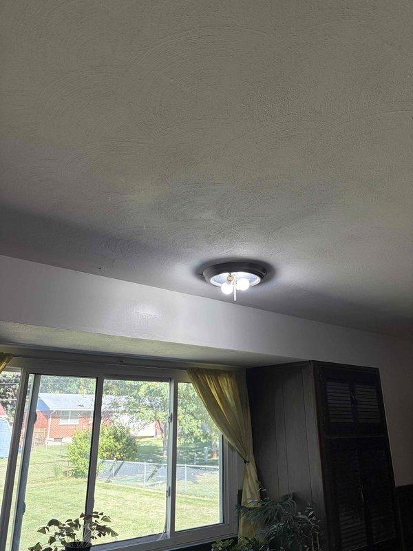 Completed installation of ceiling-mounted light fixture in residential interior space. Fixture features dark circular base with frosted glass cover, successfully wired and tested for proper illumination. All electrical connections secured to code and fixture mounting verified stable.
