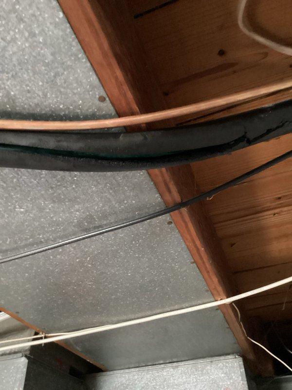 Responded to callback for condensation issue with greasy discharge from air conditioning system. Upon inspection, found improper condensate drain line installation in attic space with excessive tape repairs and compromised drainage causing water to leak onto floor below. Inspected refrigerant lines, condensate routing, and mechanical connections in ceiling cavity. Documented existing conditions showing temporary repairs to drain line that were failing, resulting in moisture accumulation and oily residue discharge. Advised on proper condensate drain line replacement and secure installation to resolve ongoing leakage issue.