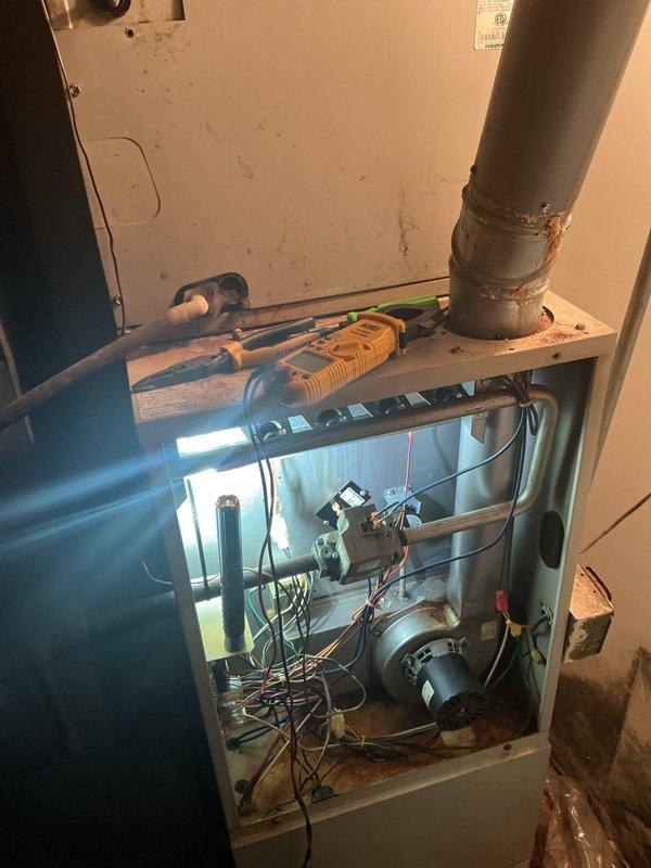 Responded to no-heat call for furnace located in garage. Unit was attempting to cycle but flame would not ignite. Upon inspection, found extensive rust and corrosion throughout the interior cabinet and blower compartment, indicating long-term moisture exposure and age-related deterioration. Removed access panel and performed diagnostic evaluation of ignition system, blower motor assembly, and electrical components. Documented heavy rust accumulation on metal housing and mounting surfaces that could affect unit reliability and safety. Photographed internal conditions showing corroded cabinet, wiring connections, and blower motor area. Presented findings and recommended repair options to address ignition failure and overall unit condition.