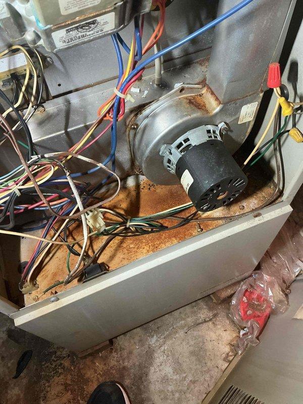 Responded to no-heat call for furnace located in garage. Unit was attempting to cycle but flame would not ignite. Upon inspection, found extensive rust and corrosion throughout the interior cabinet and blower compartment, indicating long-term moisture exposure and age-related deterioration. Removed access panel and performed diagnostic evaluation of ignition system, blower motor assembly, and electrical components. Documented heavy rust accumulation on metal housing and mounting surfaces that could affect unit reliability and safety. Photographed internal conditions showing corroded cabinet, wiring connections, and blower motor area. Presented findings and recommended repair options to address ignition failure and overall unit condition.