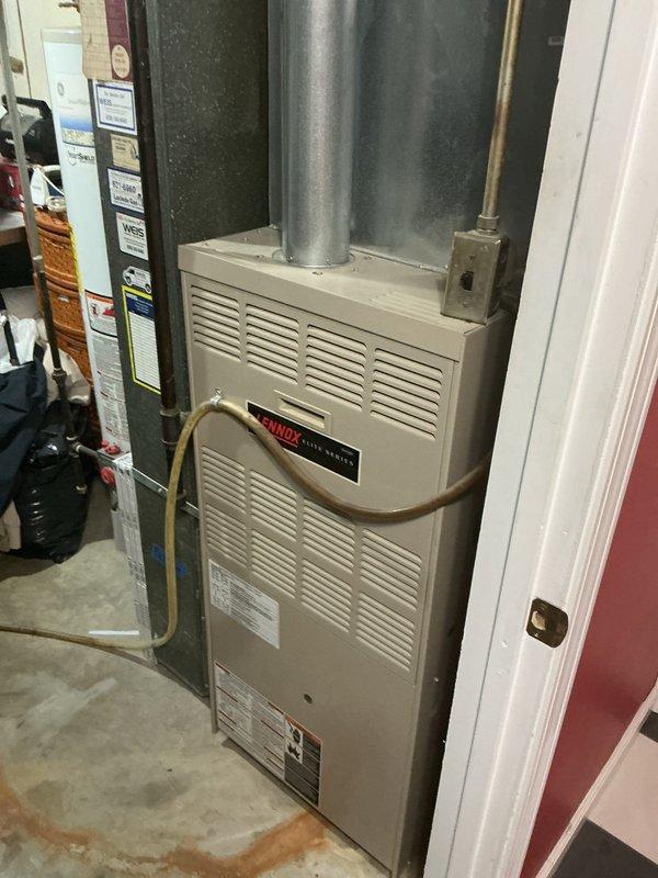 Performed a heating tune-up on a single Lennox Elite Series upflow gas furnace, inspecting the cabinet, flue venting, condensate/drain line, gas and electrical connections, and the supply ductwork and fittings for proper operation. Verified the unit and associated galvanized duct and flue components were in serviceable condition, and noted minor rust staining on the surrounding floor for monitoring.