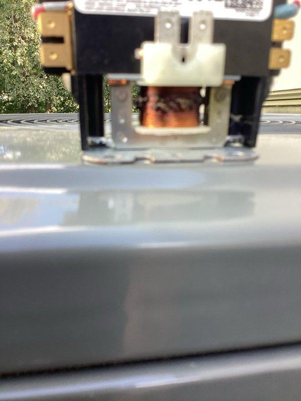 Diagnosed a no-cool, unresponsive condition on a 3-year-old split AC system and found the condenser contactor failed, with a burnt, charred coil winding and corrosion on the mounting brackets. Replaced the failed contactor, restored control voltage to the condenser, and verified the system returned to normal cooling operation.