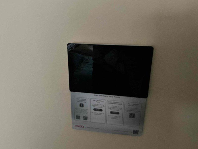 Responded to a non-responsive thermostat complaint on a two-unit system and inspected the Lennox S40 smart thermostat. The blank display was resolved and the unit is now powering on and showing normal system status, though the thermostat setup remains incomplete and requires finalizing through the manufacturer's setup process.