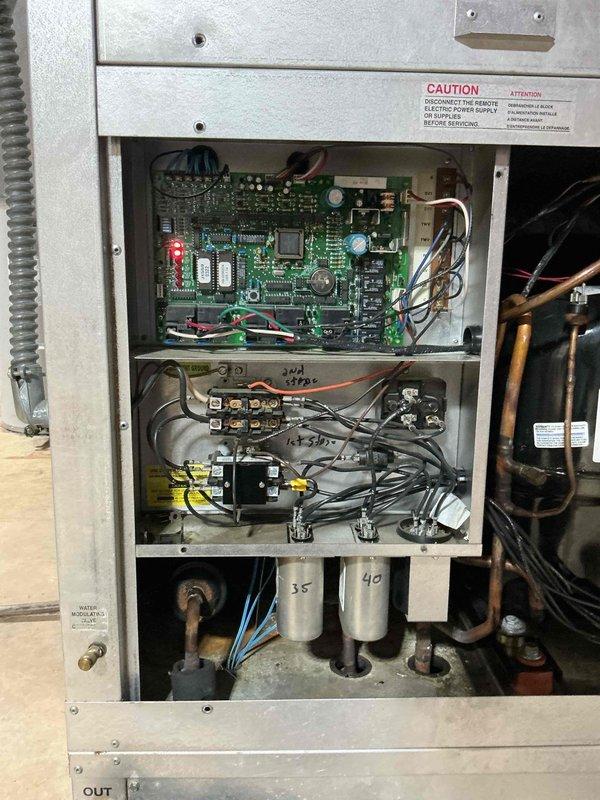 Performed a heating tune-up on a geothermal heat pump system with a functioning air handler, inspecting the control compartment, contactors, relays, wiring terminations, and run capacitors (35 and 40 µF) for signs of wear, overheating, or loose connections. Verified the control board was powered and operating, checked the refrigerant piping, compressor, water modulating valve, and condensate drain line, and found no frost, corrosion, or damage. The system was operating properly at completion.