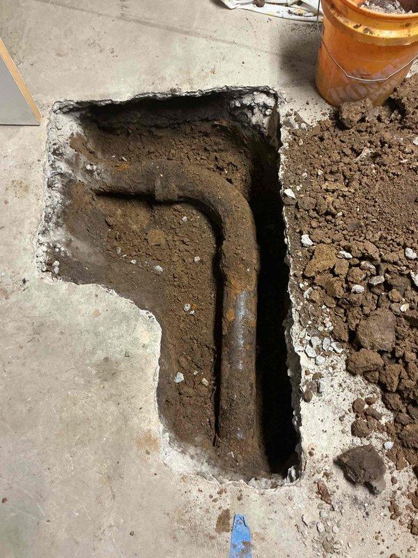 Broke out and excavated a section of the basement concrete slab to expose the deteriorated cast iron sewer lateral, then removed the corroded pipe and replaced it with new Schedule 40 PVC pipe and fittings, connected to the existing lines with band-style couplings. Backfilled the trench, restored the slab with concrete to a rough finish, and hauled away excess spoils.