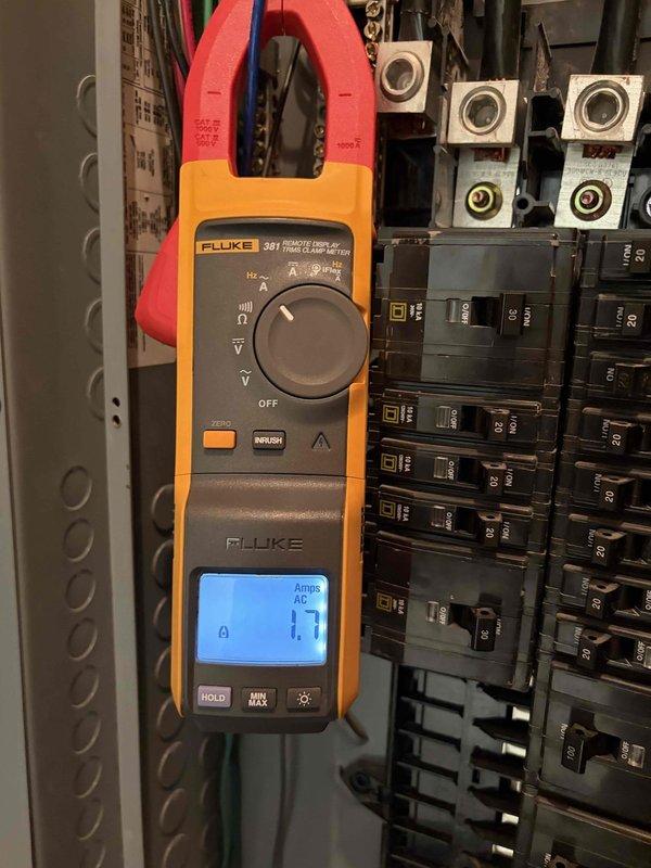Troubleshot a recurring breaker trip on the AC circuit by inspecting the commercial distribution panel and measuring circuit current with a clamp meter, which read 1.7 amps AC under the load tested. Upon removing the breakers, found discoloration and sooty residue on the breaker stab clips and housings, indicating heat-related deterioration at the connection points. Documented the condition of the panel components and breaker connections as the likely cause of the intermittent tripping.